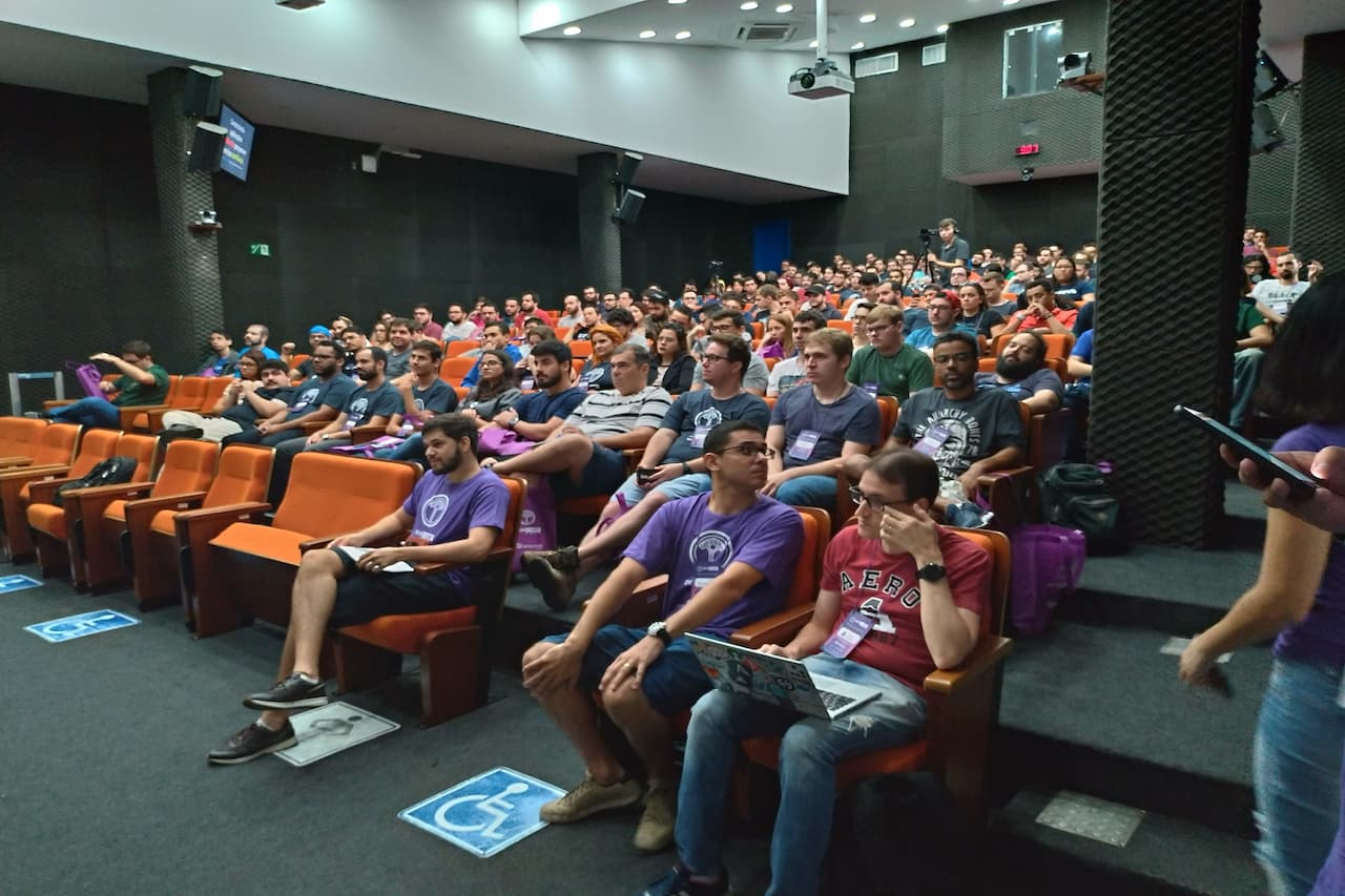 pessoas em anfiteatro ouvindo uma palestra